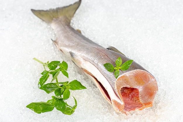 poisson entier rouge frais, allongé sur de la glace, sans tête, des tranches de citron et de citron vert sont tranchées rondes,