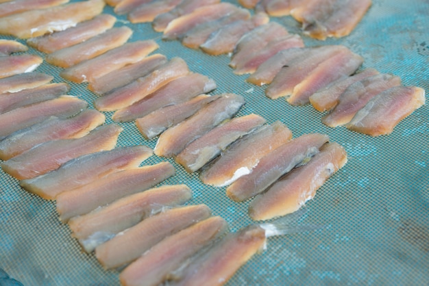 Photo poisson frais sur filet en plastique sous la lumière du soleil pour faire du poisson séché
