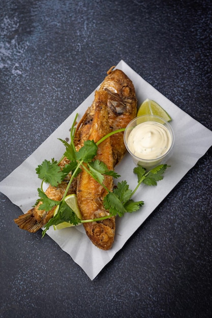 poisson frit avec légumes et sauce sur une assiette en carton jetable