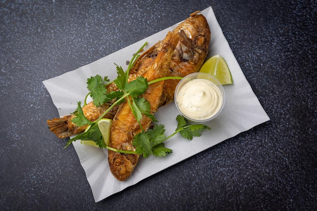 poisson frit avec légumes et sauce sur une assiette en carton jetable