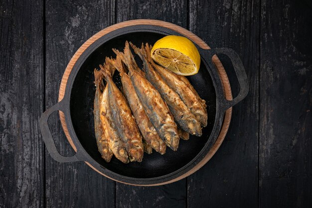 Poisson frit sur une poêle en fonte noire sur une table en bois foncé