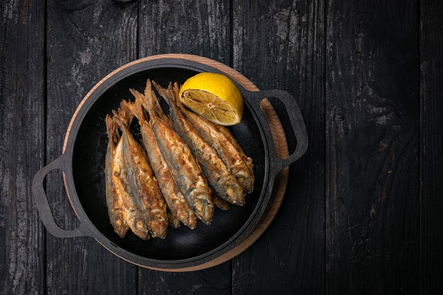 Poisson frit sur une poêle en fonte noire sur une table en bois foncé