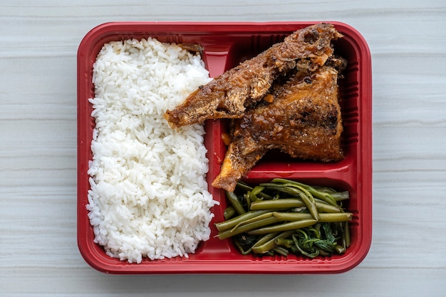 Poisson frit et riz bouilli et herbes vertes dans un récipient, gros plan, vue de dessus. Cuisine de rue au Vietnam