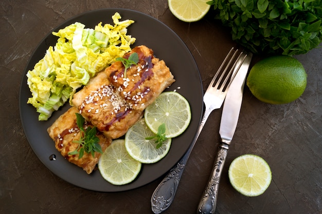 Poisson frit avec de la salade sur une assiette grise.