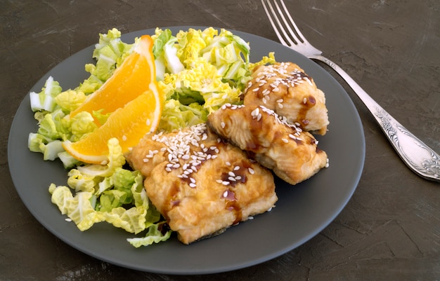 Photo poisson frit avec de la salade sur une assiette grise.