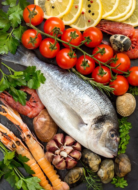 Poisson et fruits de mer dorado frais aux herbes, tomates et morceaux de citron