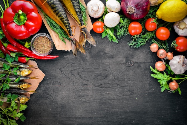 Poisson fumé sur planche de bois avec des légumes frais sur un fond en bois noir Vue de dessus