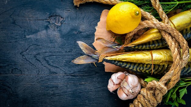 Poisson fumé sur planche de bois avec des légumes frais sur un fond en bois noir Vue de dessus