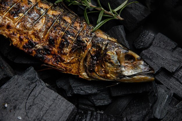 Un poisson sur un gril avec une branche de romarin dessus