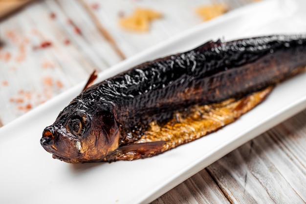 Poisson hareng fumé sur une table en bois clair plaque