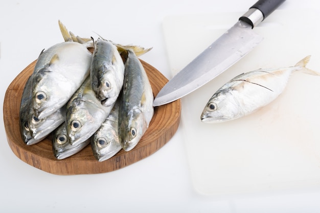 Poisson maquereau frais et couteau sur planche à découper en bois sur blanc