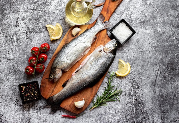 Poisson sur une planche de bois avec des citrons et des tomates