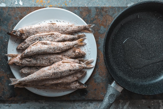 Poisson sur une poêle à frire sur un fond gris beige