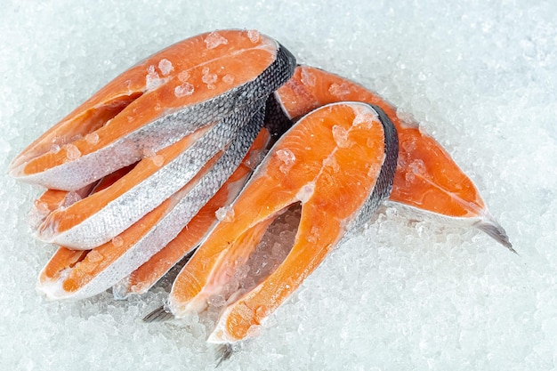 le poisson rouge de l'océan de mer frais est coupé en morceaux, se trouve sur la glace, sans tête, cerise, tranches de citron et