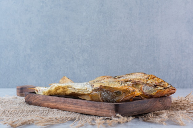 Poisson séché salé isolé sur une planche de bois.