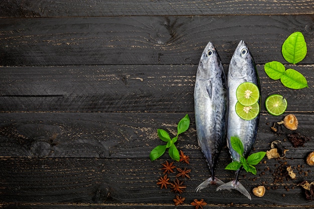 Poisson thon frais sur fond en bois noir foncé, poisson avec des épices et des légumes