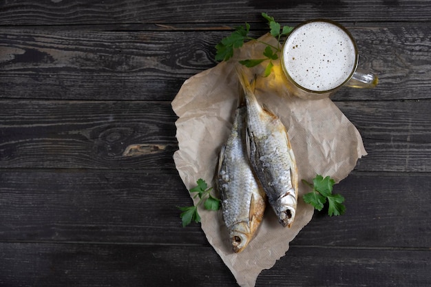 Poisson vobla séché salé avec de la bière ambrée sur un fond en bois foncé avec du pain sur la table à plat avec espace de copie