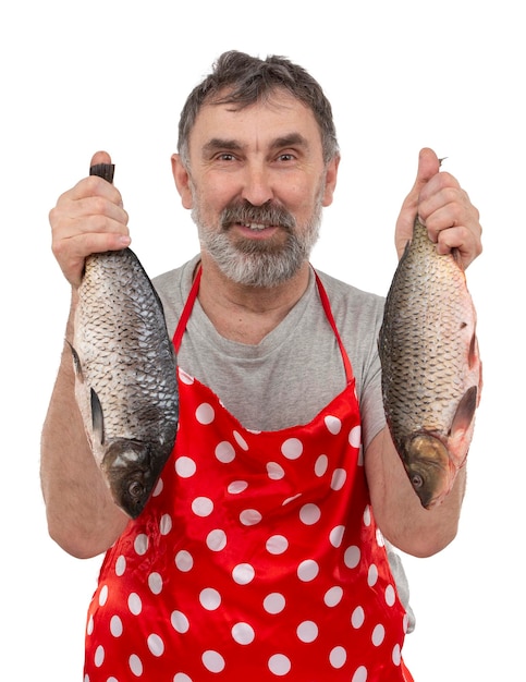 Photo poissonnier mature en tablier rouge tenant de gros poissons d'eau douce et regardant la caméra sur fond blanc