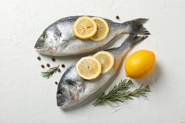 Poissons Dorado frais, poivre, citron et romarin sur fond blanc, vue du dessus