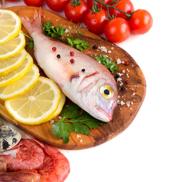 Photo poissons et fruits de mer frais avec des morceaux de citron, des tomates et des herbes