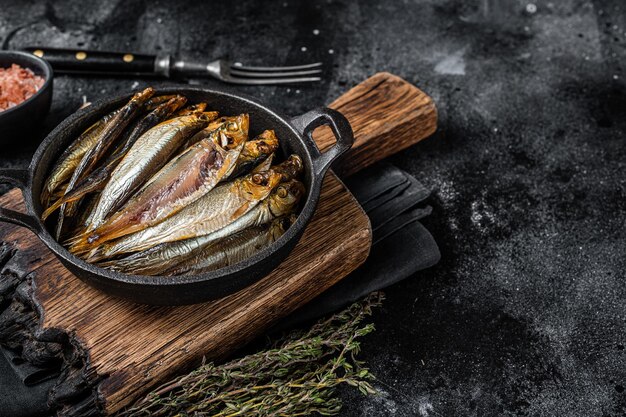 Poissons de sprat et d'anchois fumés à chaud dans une casserole Fond noir Vue de dessus Espace de copie