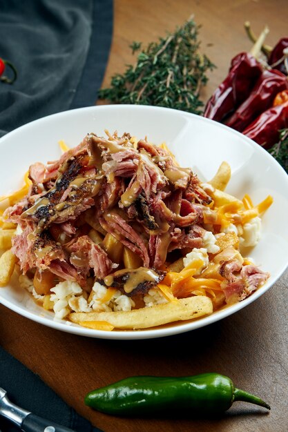 Poitrine de boeuf fumeur avec sauce aux arachides et un plat d'accompagnement de frites dans un bol blanc sur une table en bois. Boeuf au four. un barbecue