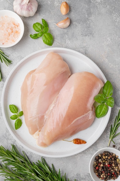 Poitrine ou filet de poulet cru avec du sel, du poivre et des herbes fraîches Aliments sains Vue de dessus espace de copie