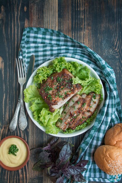 Poitrine de porc au four aux épices. Poitrine en tranches servie avec des légumes verts. Plat traditionnel d'Ukraine. Fermer. Espace pour le texte.