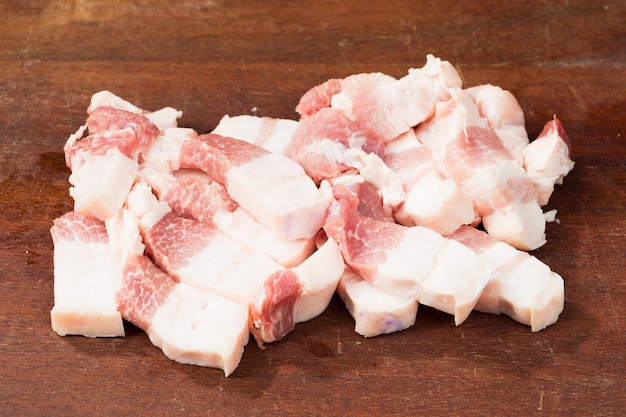 Poitrine de porc fraîche coupée en dés sur une planche à découper