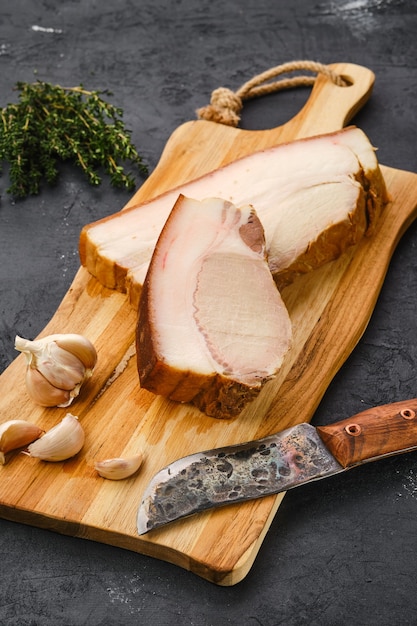 Poitrine de porc fumée à froid sur une planche à découper en bois