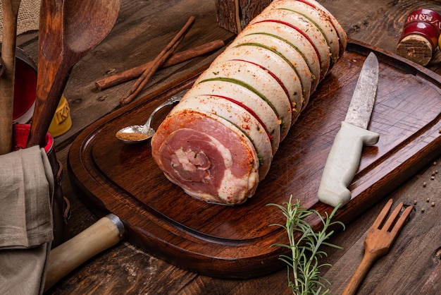 Poitrine de porc roulée sur planche de bois et épices