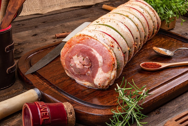 Poitrine de porc roulée sur planche de bois et épices