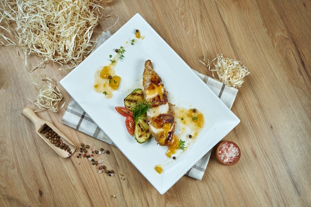 Poitrine de poulet au four appétissante avec du fromage, des légumes et une sauce sucrée sur une plaque blanche. Nourriture diététique. Fermer. Mise à plat