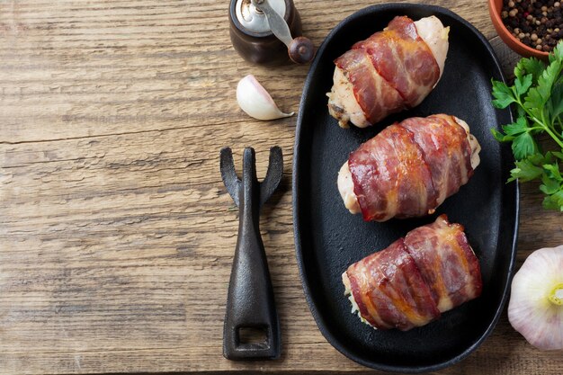 Poitrine de poulet au four enveloppée de bacon sur une poêle en fonte sur un vieux bois