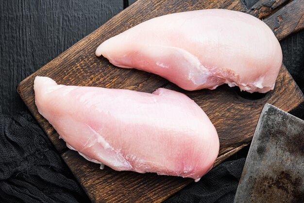 Poitrine de poulet avec couteau de boucher sur la vue de dessus de table en bois noir