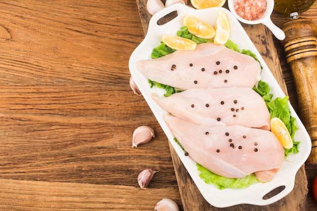 Poitrine de poulet cru et épices sur planche à découper en bois