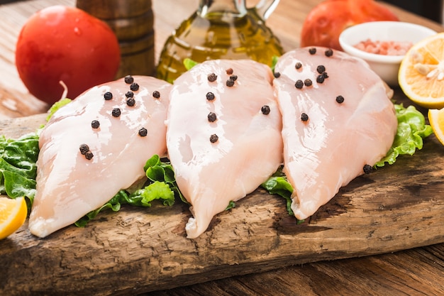 Poitrine de poulet cru et épices sur planche à découper en bois