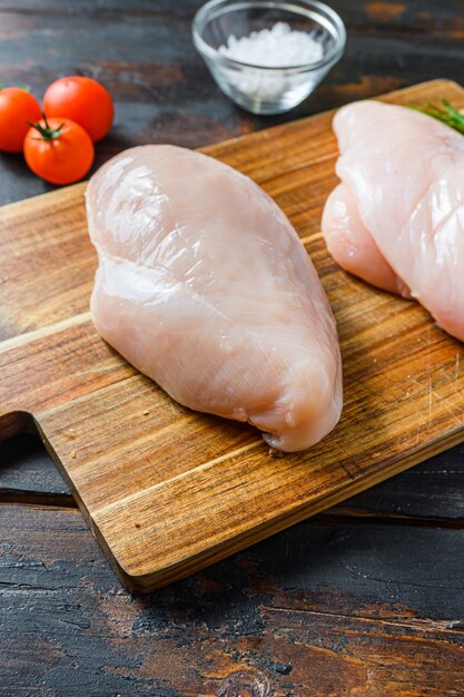 Photo poitrine de poulet cru et épices sur planche à découper en bois