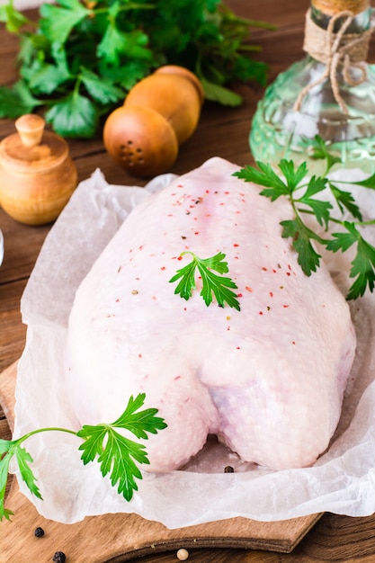 Poitrine de poulet crue sur un cadre d'épices et d'herbes sur une planche à découper sur une table en bois