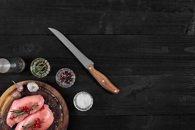 Poitrine de poulet crue et condiments dans une vue de dessus de cadre en bois rustique