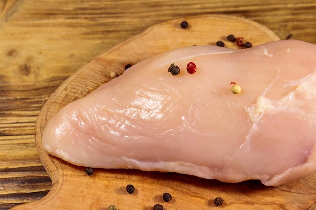 Poitrine de poulet crue sur une planche à découper sur une table en bois