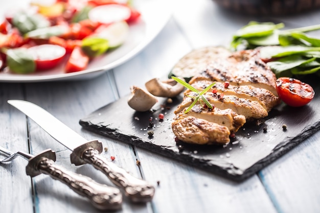 Poitrine de poulet grillée sur ardoise, épinards aux herbes, tomates et autres légumes.