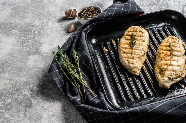 Photo poitrine de poulet grillée dans une poêle avec du thym et de l'ail