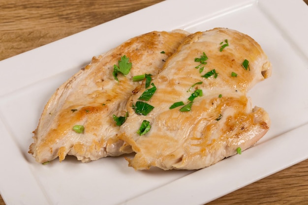 Poitrine de poulet grillée sur plat blanc sur fond de bois