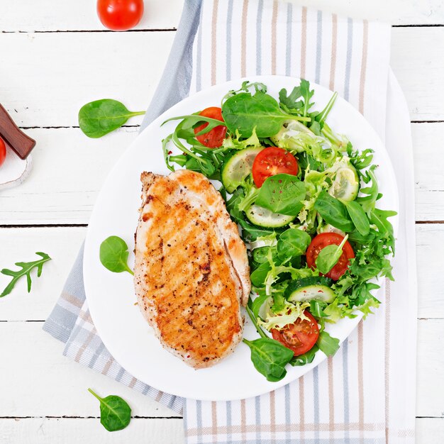 Poitrine de poulet grillée et salade de légumes frais - tomates, concombres et feuilles de laitue. Salade de poulet. Nourriture saine. Mise à plat.