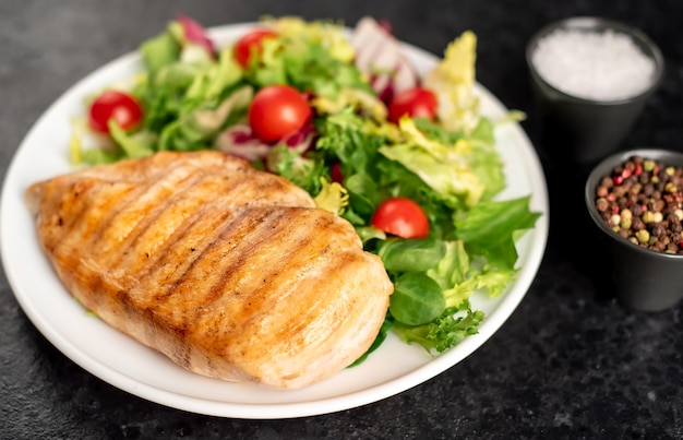 poitrine de poulet grillée et salade de tomates cerises sur fond de pierre