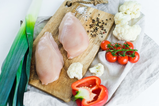 Photo poitrines de poulet crues sur une planche à découper en bois.