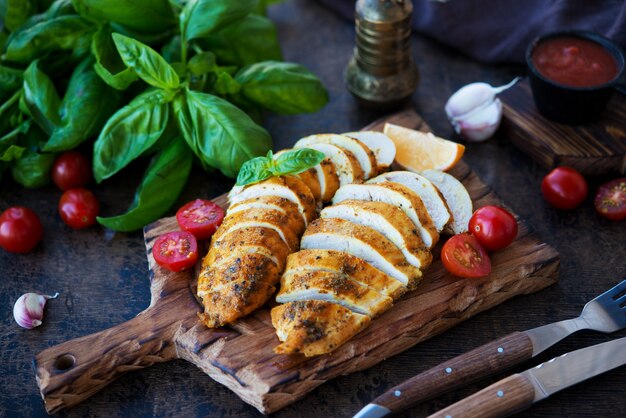 Poitrines de poulet cuites au four sur une planche de bois avec des légumes, mise au point sélective