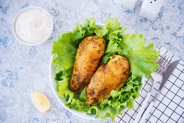 Poitrines de poulet cuites dans des épices et de l'huile avec des herbes fraîches pour le dîner, nourriture saine sur fond clair, mise au point sélective, vue de dessus