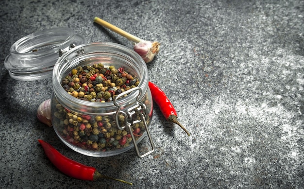 Poivre dans un bocal en verre avec de l'ail. Sur une table rustique.